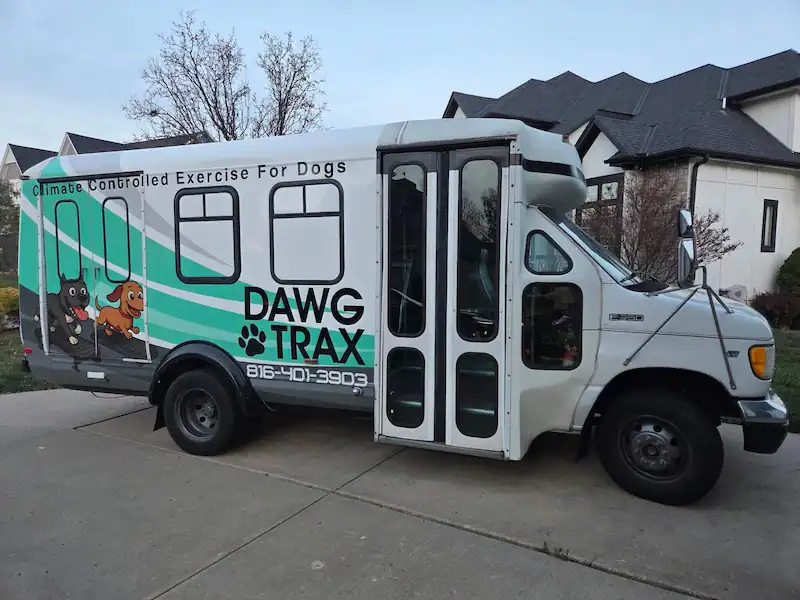 Driver’s side view of the Dawg Trax bus parked in front of a suburban home (Side view of Dawg Trax van in driveway)
